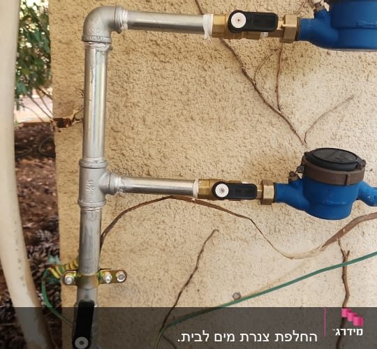 צינורות מתכת עם ברזים ומדי מים על קיר